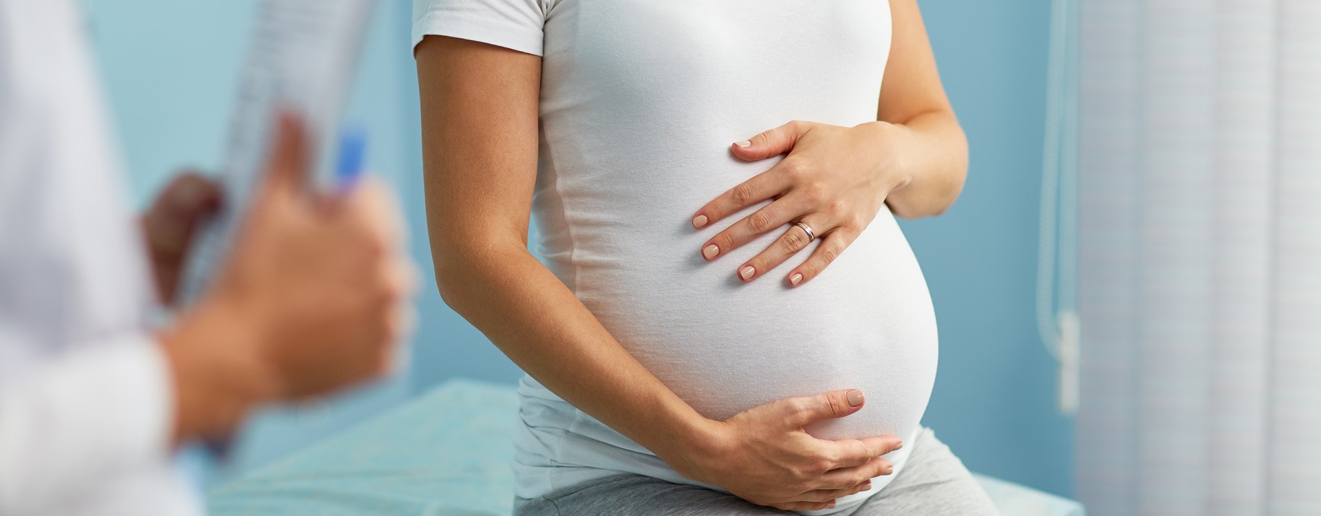 Schwangere beim Arzt hält sich ihren Bauch